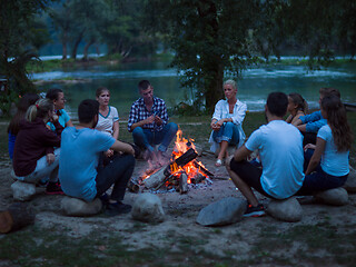 Image showing young friends relaxing around campfire