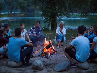 Image showing young friends relaxing around campfire