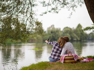 Image showing Couple taking a selfie by mobile phone while enjoying picnic tim