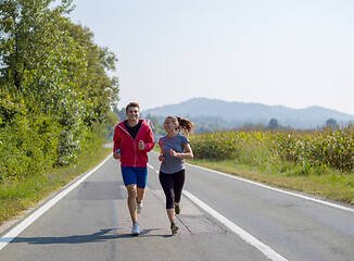 Image showing young couple jogging along a country road