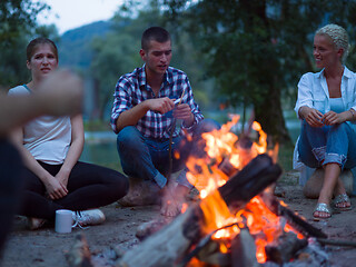 Image showing young friends relaxing around campfire