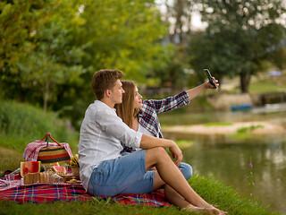 Image showing Couple taking a selfie by mobile phone while enjoying picnic tim