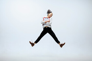 Image showing Woman working at office and jumping isolated on studio background