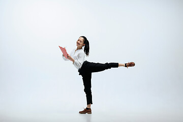 Image showing Woman working at office and jumping isolated on studio background