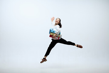 Image showing Woman working at office and jumping isolated on studio background