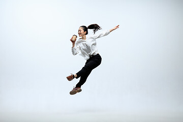 Image showing Woman working at office and jumping isolated on studio background