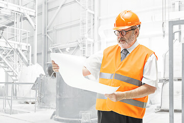 Image showing The builder in orange helmet against industrial background