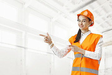 Image showing Destroying gender stereotypes. Female builder standing against industrial background