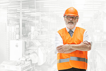 Image showing Professional senior builder in orange helmet against industrial background