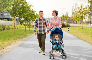 Image showing family with baby and stroller walking along city