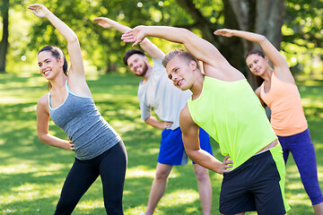 Image showing group of happy people exercising at summer park