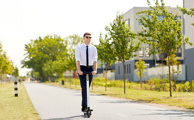 Image showing young businessman riding electric scooter in city