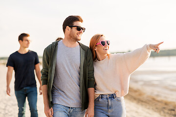 Image showing happy friends walking along summer beach