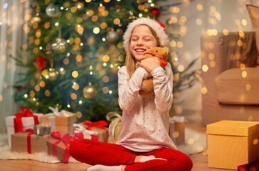 Image showing smiling girl in santa hat with christmas gift