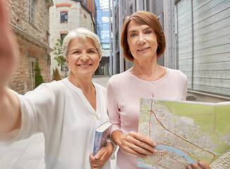 Image showing senior women with map and city guide taking selfie