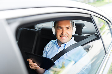 Image showing passenger with headphones using tablet pc in car