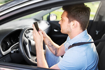 Image showing man driving car and using smartphone