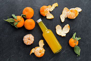 Image showing glass bottle of fruit juice and peeled mandarins