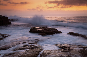 Image showing Coastal sunrise waves crashing onto rocks