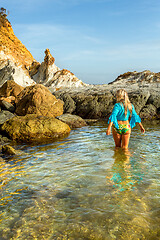 Image showing Woman wading into natural rock pool in early morning light