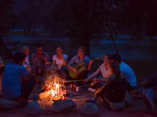 Image showing young friends relaxing around campfire