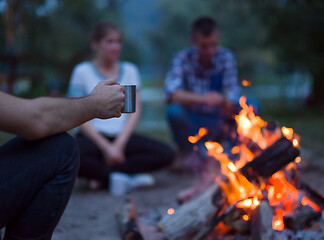 Image showing young friends relaxing around campfire