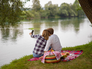 Image showing Couple taking a selfie by mobile phone while enjoying picnic tim