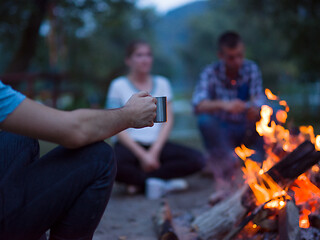 Image showing young friends relaxing around campfire