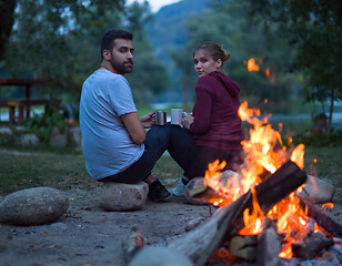 Image showing couple sitting around the campfire at evening