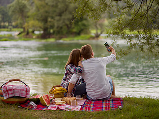 Image showing Couple taking a selfie by mobile phone while enjoying picnic tim