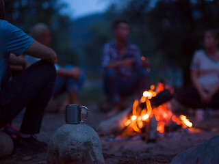 Image showing young friends relaxing around campfire