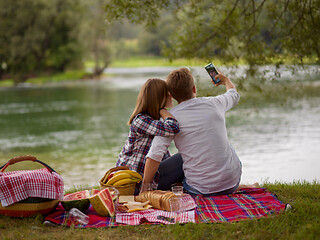 Image showing Couple taking a selfie by mobile phone while enjoying picnic tim