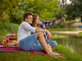 Image showing Couple taking a selfie by mobile phone while enjoying picnic tim