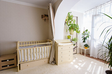 Image showing A newborn baby\'s crib and a changing table stand at the entrance to the glazed balcony