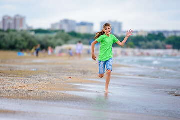 Image showing A girl of ten runs joyfully along the seashore