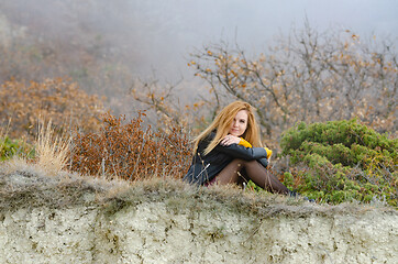 Image showing Girl sitting on a hill against the background of a foggy forest