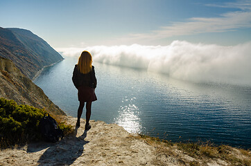 Image showing A girl stands on a hill and observes an unusual phenomenon of nature over the sea