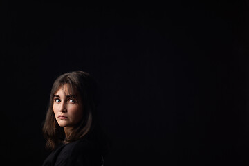 Image showing The girl looks at the empty space around her, black background