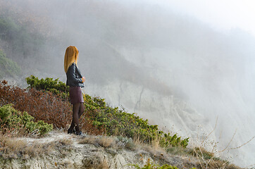 Image showing The girl watches the foggy sunrise in the mountains