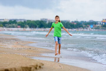 Image showing The girl runs happily along the sea coast