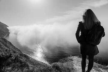 Image showing Girl watching from the mountain for the fog over the sea, black and white photography