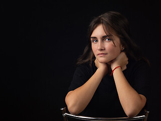 Image showing Portrait of a young girl with her elbows on the back of a chair, the girl looks into the frame