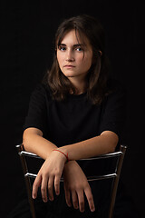 Image showing Portrait of a young girl sitting on a high chair with her hands folded on the back of the chair