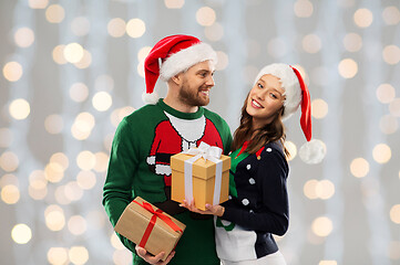 Image showing happy couple in christmas sweaters with gifts