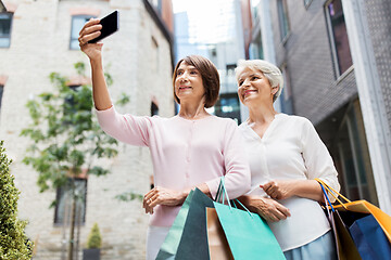 Image showing old women with shopping bags taking selfie in city