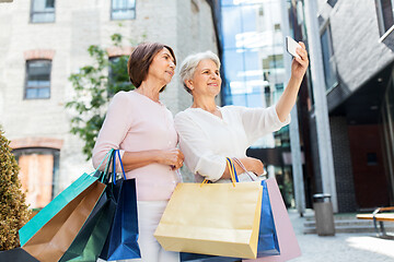 Image showing old women with shopping bags taking selfie in city