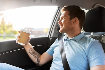 Image showing man with takeaway coffee on back seat of taxi car