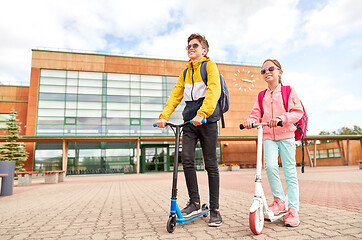 Image showing happy school children with backpacks and scooters