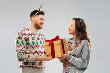 Image showing happy couple in christmas sweaters with gift box