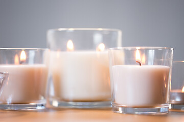 Image showing burning white fragrance candles on wooden table